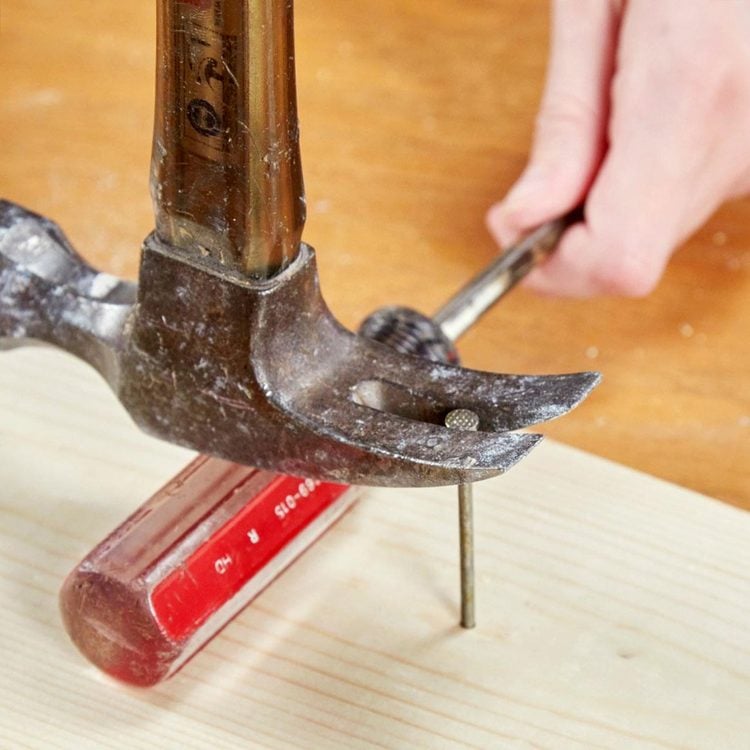 Un marteau utilise la poignée d'un tournevis comme cale pour arracher un clou.