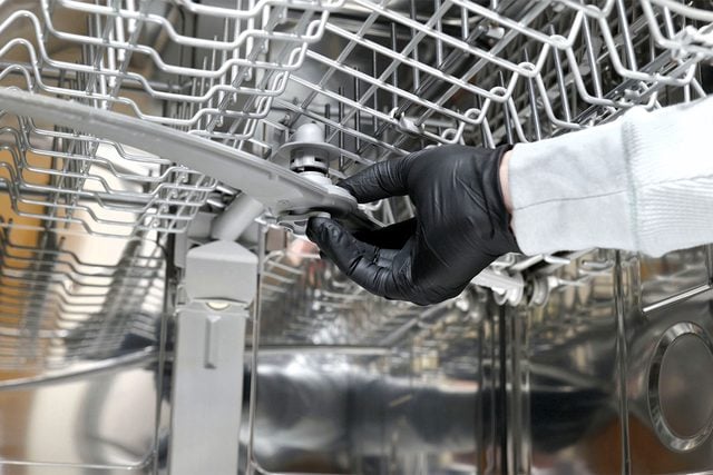 Une main dévisse et enlève le bras de lavage inférieur.