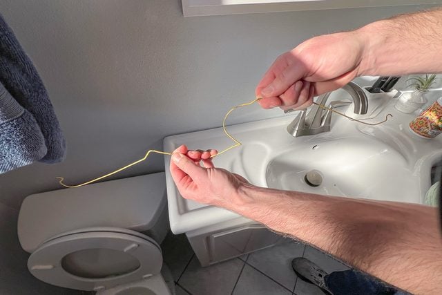 Un cintre en métal en train d'être déplié à la main.