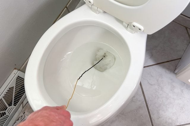 Le cintre déplié est utilisé pour triturer le bouchon au fond de la cuvette des toilettes.