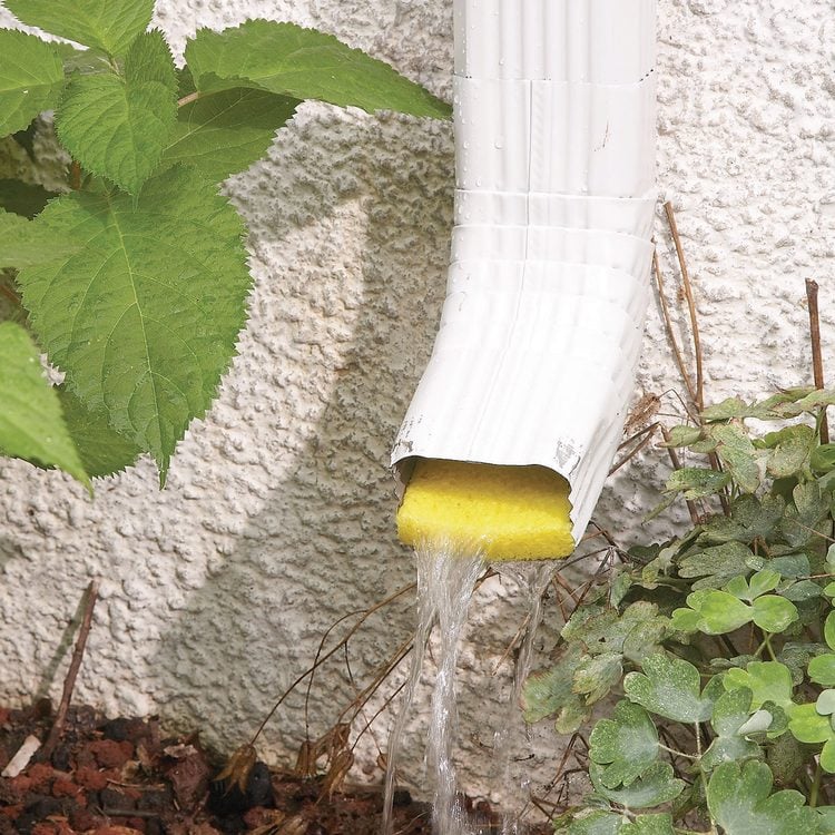 Une gouttière blanche déverse de l'eau sur une éponge jaune qui absorbe le flux.
