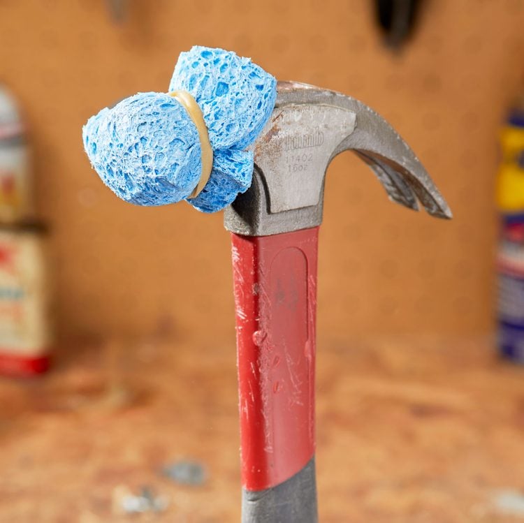 Un marteau dont la tête est recouverte d'une éponge bleue maintenue par un élastique.