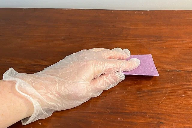 Personne qui ponce le bois avec du papier de verre.