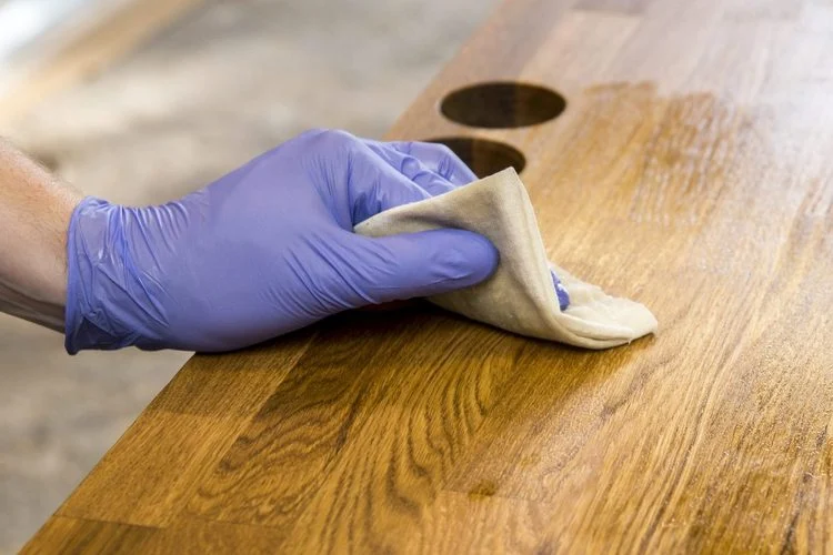 personne huilant un plan de travail en bois de cuisine avec un chiffon