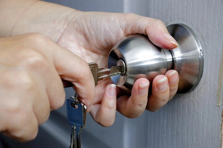 femme insérant une clé dans la serrure d'une porte d'entrée