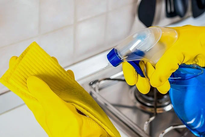 Une personne nettoie un appareil en inox avec un chiffon.