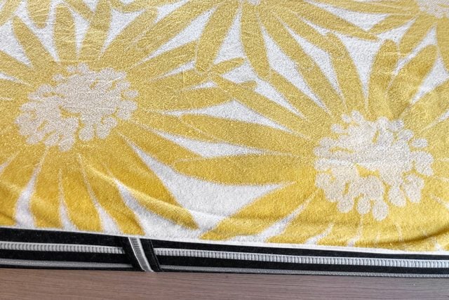 Une serviette à motifs floraux jaunes posée sur une surface sombre.