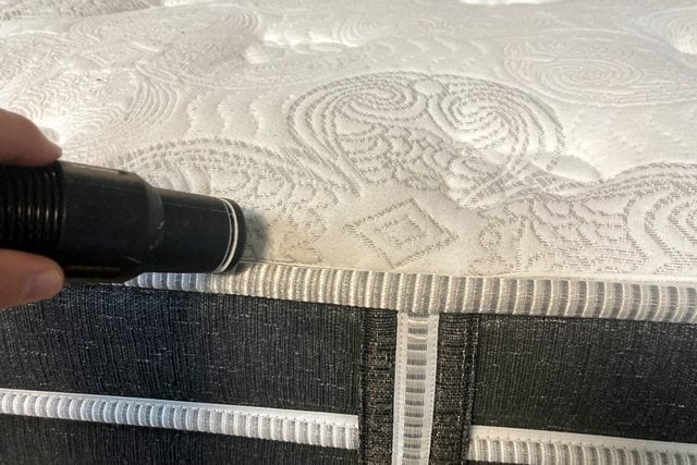 Une main tenant une lampe de poche pour éclairer la surface texturée d'un matelas.