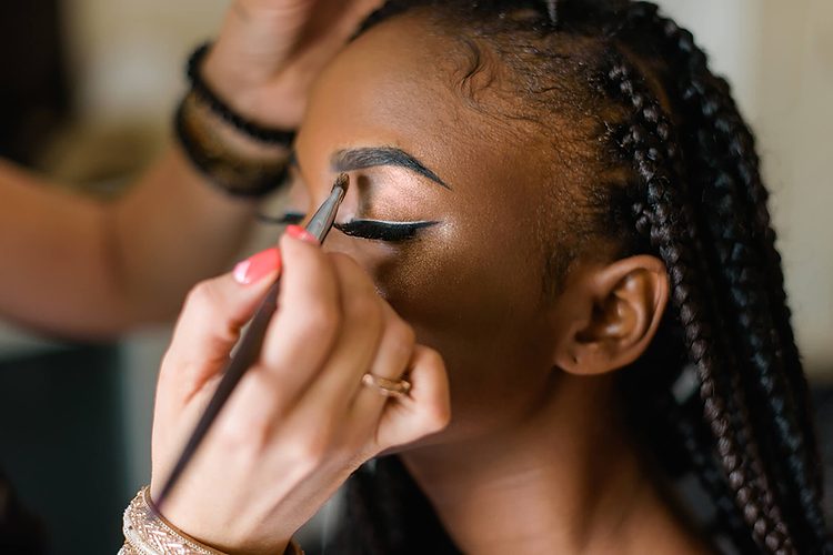Une personne appliquant du maquillage sur l'œil d'une autre personne.