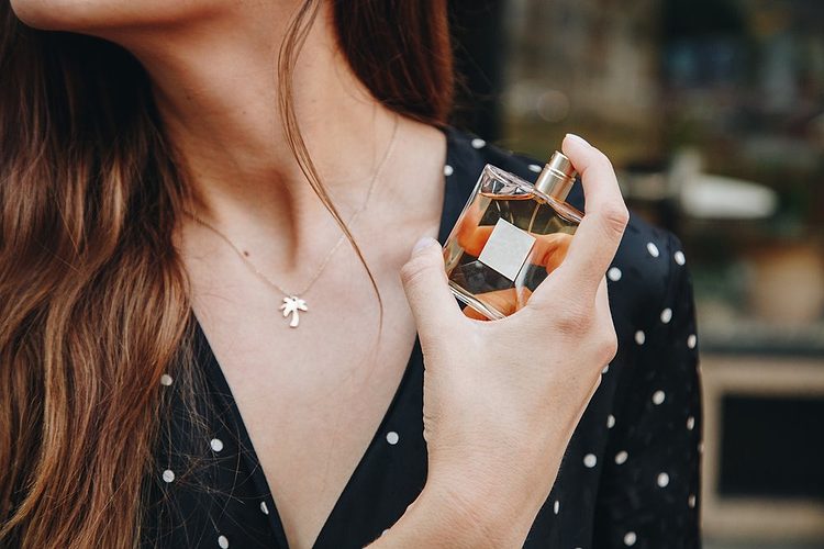 Une femme vaporisant du parfum sur son cou.