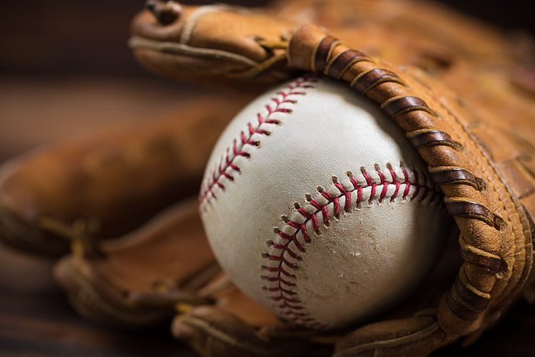 Une balle de baseball dans un gant en cuir marron.