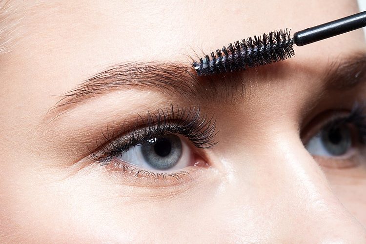 Gros plan sur une personne se brossant les sourcils.