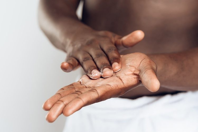 Une personne se frottant les mains avec de la crème.