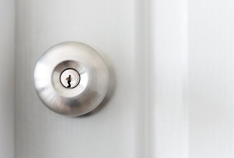 Une poignée de porte métallique sur une porte blanche.