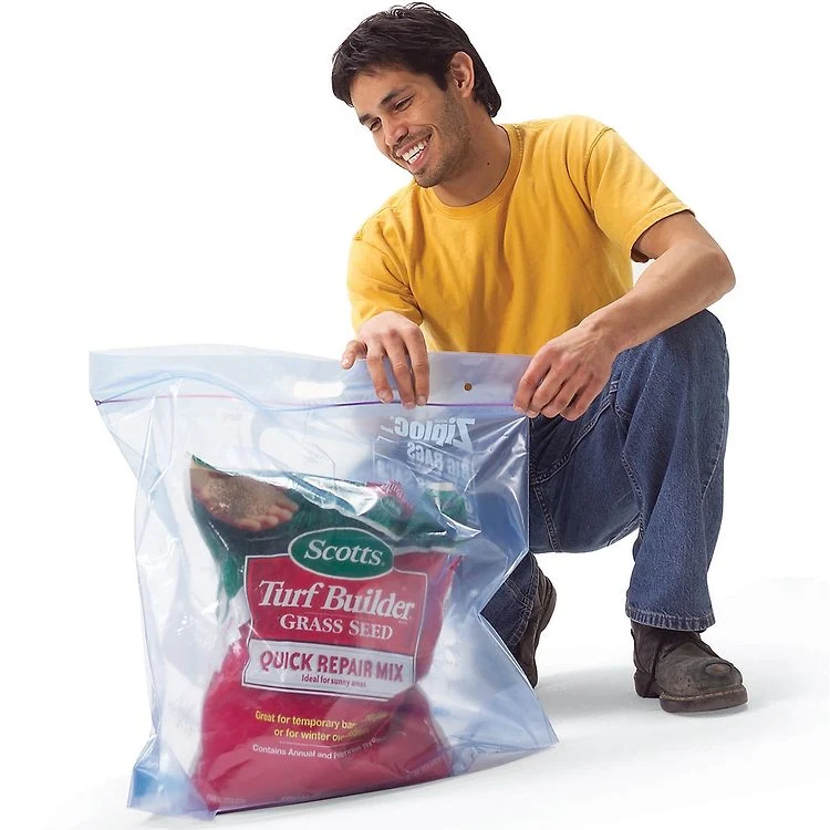 Un homme tenant un grand sac refermable contenant des semences de gazon.