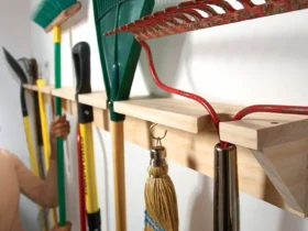 Des outils de jardin suspendus à un râtelier mural en bois.