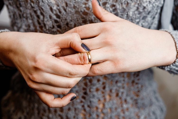 Une main essayant de retirer une bague d'un doigt.