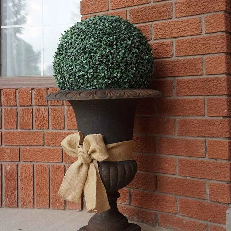 un pot de fleurs rustique en métal avec un noeud en toile de jute