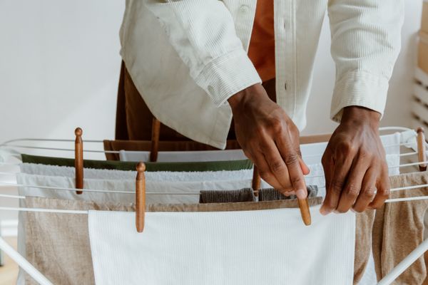 mains espaçant des vêtements sur un étendoir